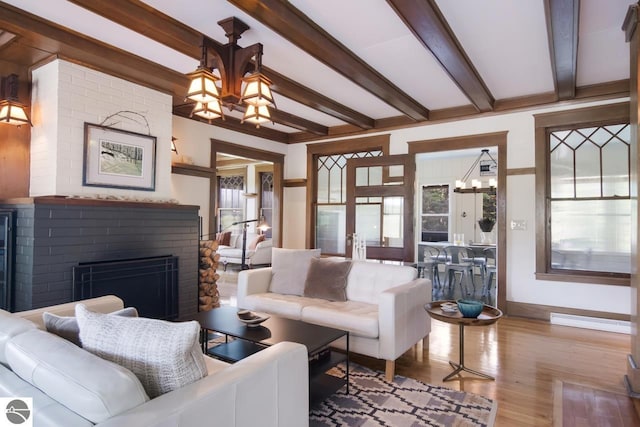 living room with a fireplace, beamed ceiling, light hardwood / wood-style floors, and a notable chandelier