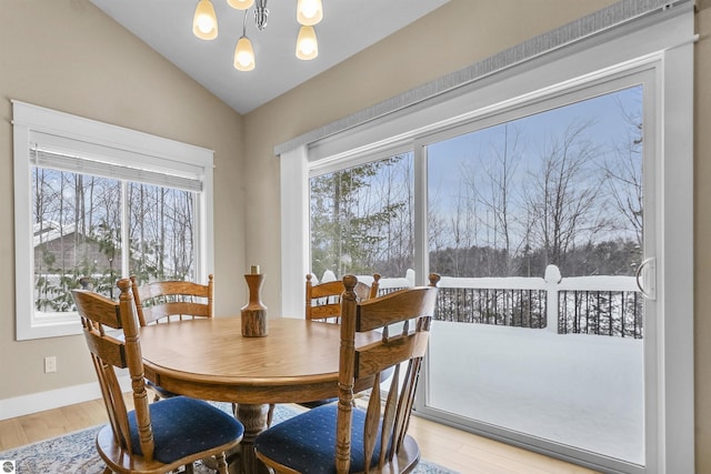 dining room featuring hardwood / wood-style flooring, lofted ceiling, and a chandelier