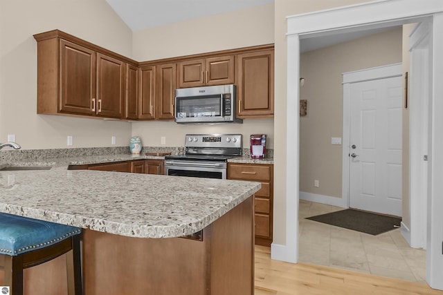 kitchen with appliances with stainless steel finishes, a kitchen bar, kitchen peninsula, and sink