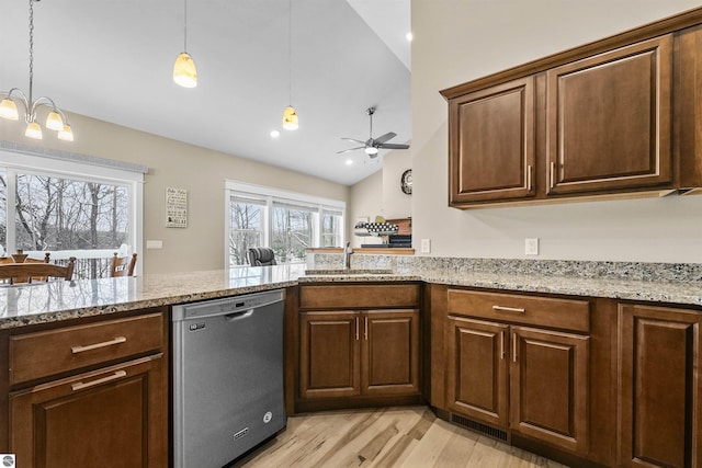 kitchen featuring pendant lighting, lofted ceiling, sink, stainless steel dishwasher, and light hardwood / wood-style flooring