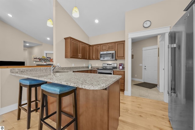 kitchen with light hardwood / wood-style floors, pendant lighting, kitchen peninsula, a breakfast bar area, and stainless steel appliances