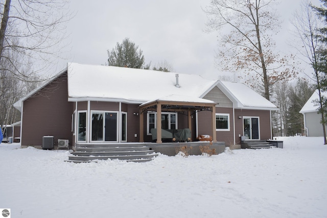 snow covered back of property with cooling unit and covered porch