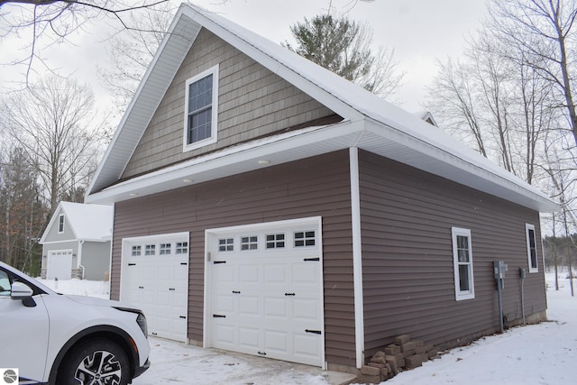 view of snowy exterior with a garage and an outbuilding