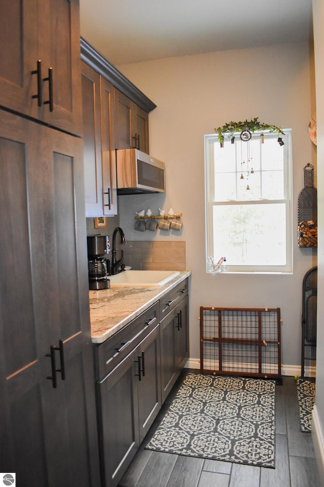 kitchen featuring dark wood-type flooring, decorative backsplash, dark brown cabinets, and sink