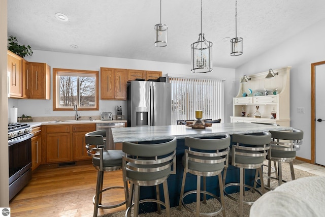 kitchen with stainless steel appliances, sink, hanging light fixtures, and a center island