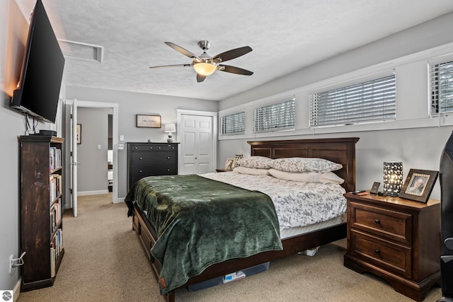 bedroom featuring ceiling fan, a textured ceiling, a closet, and light carpet