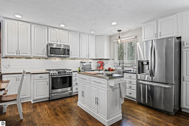 kitchen featuring white cabinets, decorative light fixtures, dark hardwood / wood-style flooring, stainless steel appliances, and sink