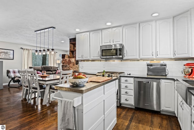 kitchen with pendant lighting, white cabinetry, stainless steel appliances, tasteful backsplash, and dark hardwood / wood-style floors