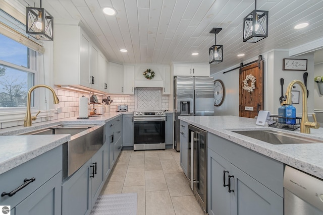 kitchen with appliances with stainless steel finishes, decorative light fixtures, white cabinetry, backsplash, and a barn door