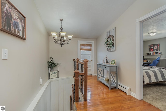 hallway with wood-type flooring, a textured ceiling, and a chandelier