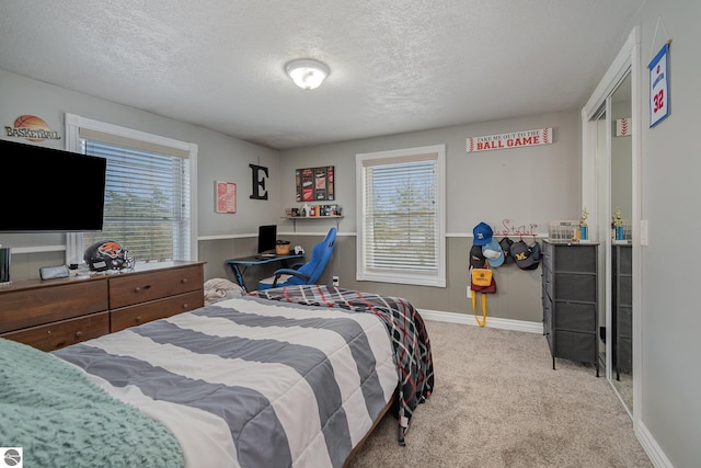 bedroom with light carpet, a textured ceiling, and multiple windows