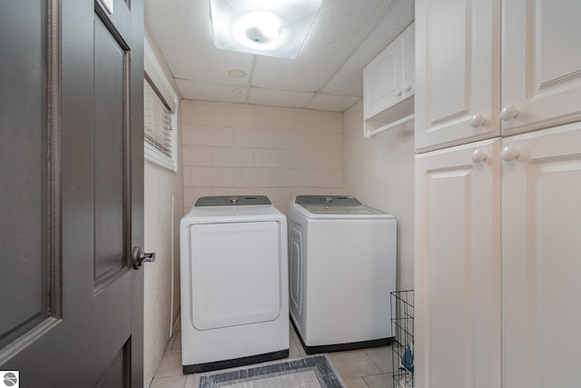 laundry area featuring washer and dryer, cabinets, and light tile patterned flooring