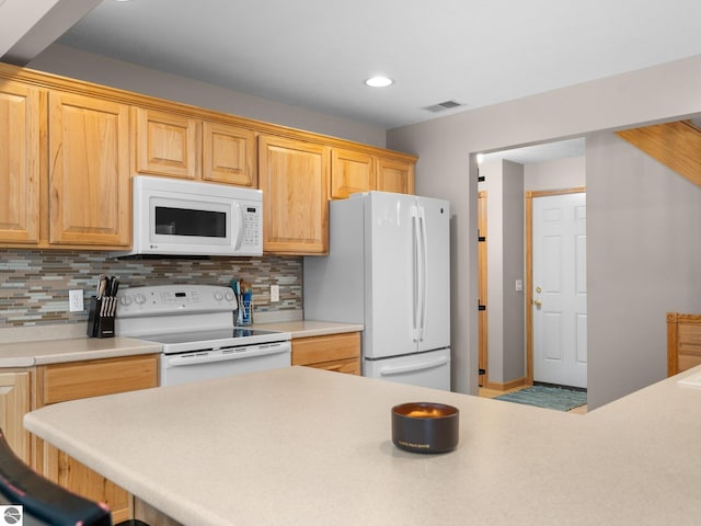 kitchen with light brown cabinets, a kitchen bar, white appliances, and decorative backsplash