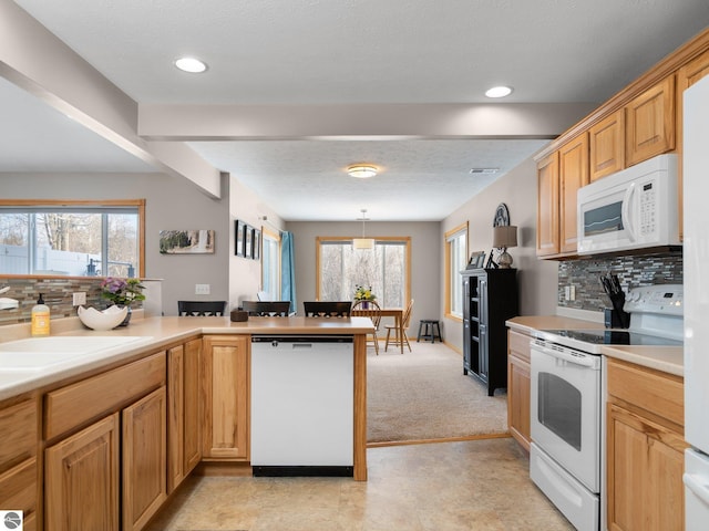 kitchen with light carpet, decorative light fixtures, white appliances, a healthy amount of sunlight, and decorative backsplash