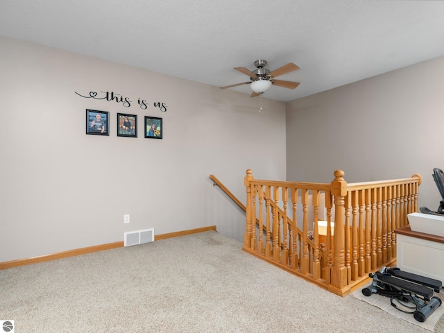 stairs featuring ceiling fan and carpet