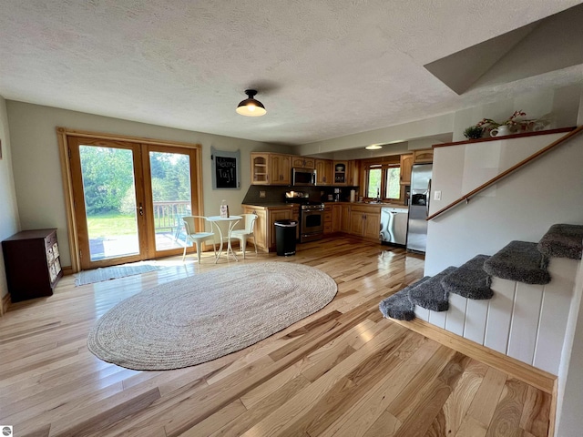 living room featuring a textured ceiling, light hardwood / wood-style flooring, and french doors