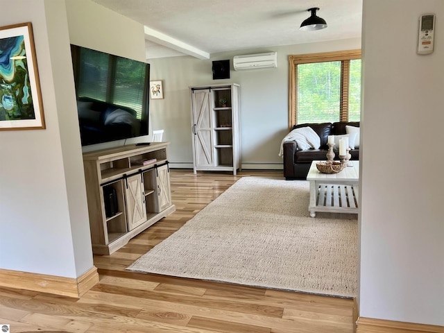 living room featuring a baseboard heating unit, light hardwood / wood-style flooring, a barn door, and a wall mounted air conditioner