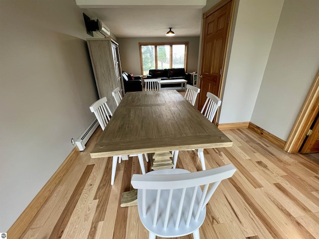 dining space with a baseboard radiator, a wall mounted air conditioner, and light hardwood / wood-style flooring