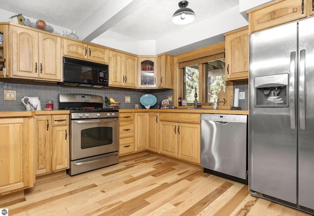 kitchen featuring sink, backsplash, light hardwood / wood-style flooring, and appliances with stainless steel finishes