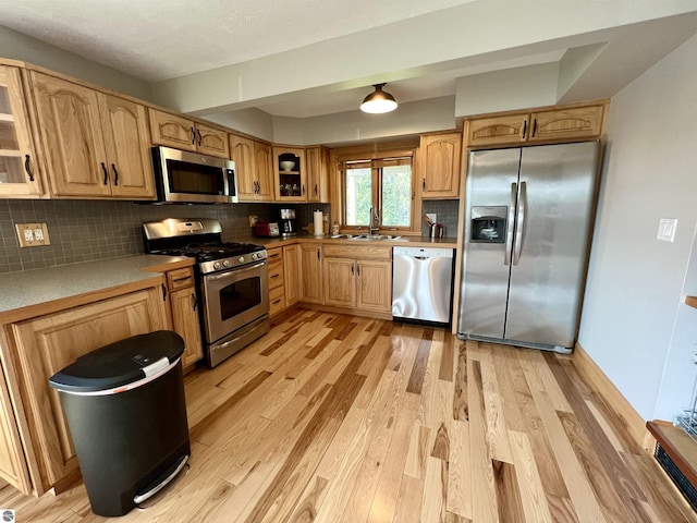 kitchen featuring light brown cabinetry, appliances with stainless steel finishes, sink, backsplash, and light wood-type flooring