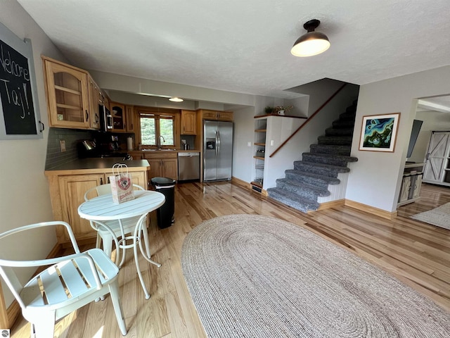 kitchen featuring light wood-type flooring, backsplash, appliances with stainless steel finishes, and sink