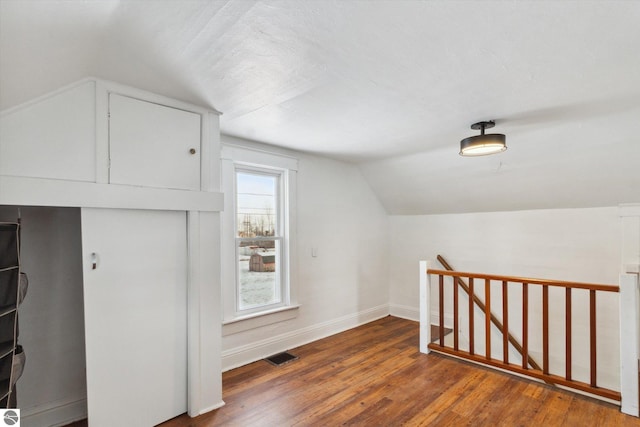 additional living space with dark hardwood / wood-style floors and vaulted ceiling