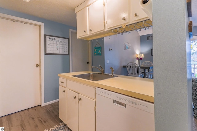 kitchen with hardwood / wood-style flooring, sink, white cabinetry, and dishwasher