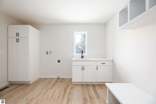 laundry area featuring sink, hookup for an electric dryer, light hardwood / wood-style floors, and hookup for a washing machine