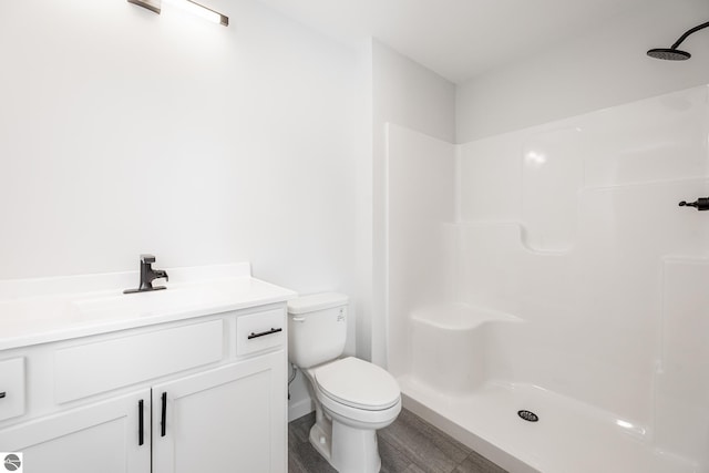 bathroom featuring toilet, a shower, and vanity