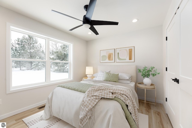 bedroom featuring ceiling fan, multiple windows, and light wood-type flooring