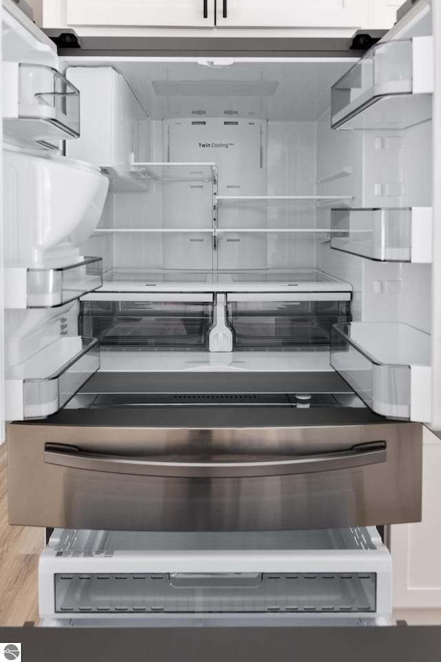 room details featuring white cabinets, hardwood / wood-style flooring, and fridge