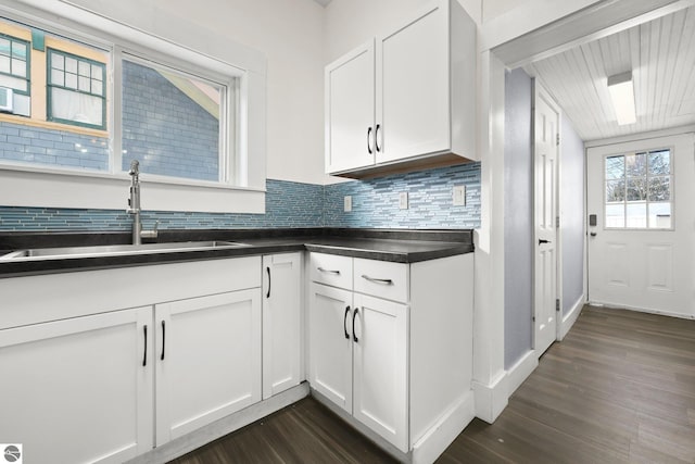 kitchen with sink, white cabinetry, dark hardwood / wood-style floors, and decorative backsplash