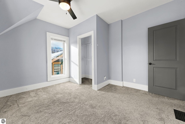 unfurnished bedroom with carpet, a closet, vaulted ceiling, and ceiling fan