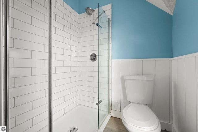 bathroom featuring toilet, tiled shower, a textured ceiling, and wood-type flooring