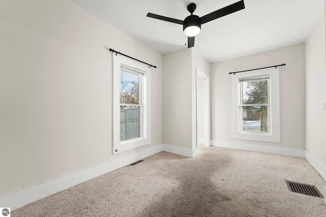 carpeted empty room with a healthy amount of sunlight and ceiling fan