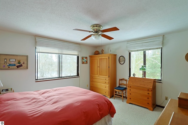 carpeted bedroom featuring ceiling fan, a textured ceiling, and multiple windows