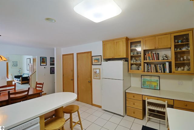 kitchen featuring white appliances, light tile patterned floors, and built in desk