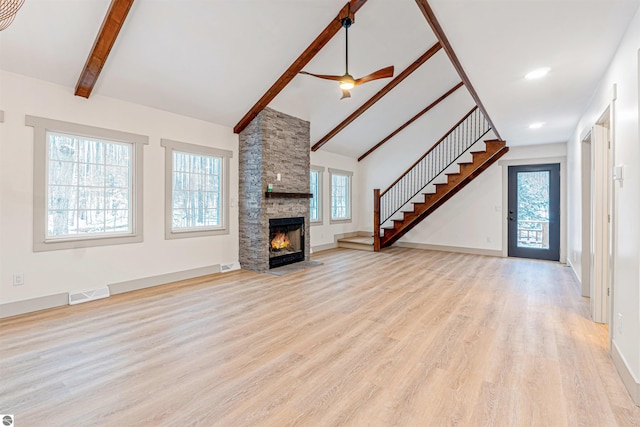 unfurnished living room with a stone fireplace, beamed ceiling, light hardwood / wood-style floors, high vaulted ceiling, and ceiling fan