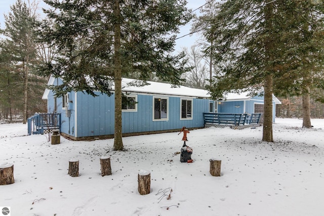 snow covered rear of property featuring a wooden deck