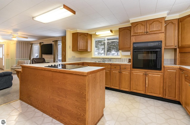 kitchen with black appliances, tile counters, sink, ceiling fan, and crown molding