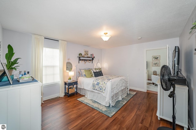 bedroom featuring a textured ceiling and dark hardwood / wood-style flooring