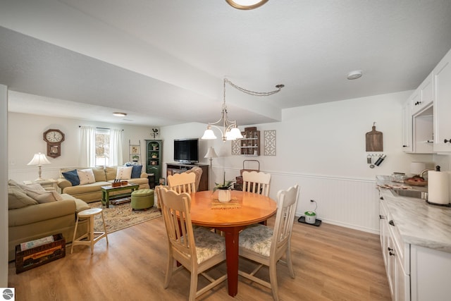 dining area with sink, light hardwood / wood-style flooring, a notable chandelier, and a textured ceiling