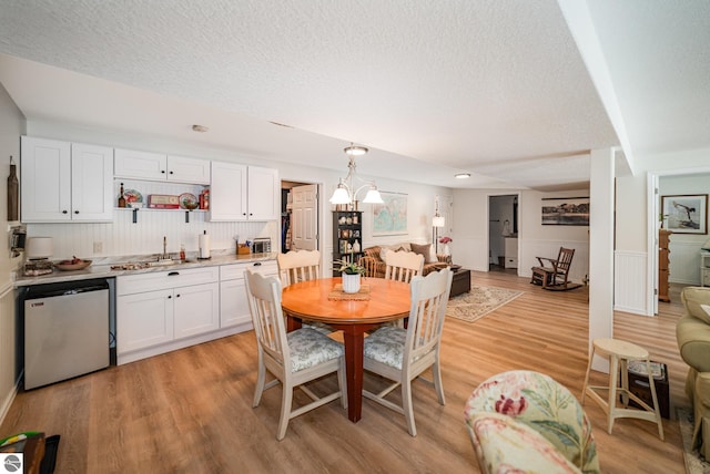 dining space featuring sink, light hardwood / wood-style flooring, and an inviting chandelier