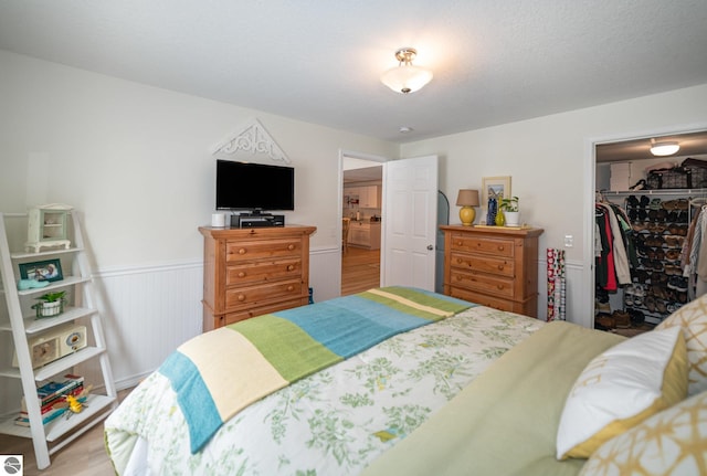 bedroom featuring light hardwood / wood-style floors, a textured ceiling, a closet, and a walk in closet