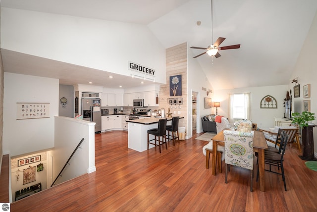 dining room with high vaulted ceiling, hardwood / wood-style flooring, and ceiling fan