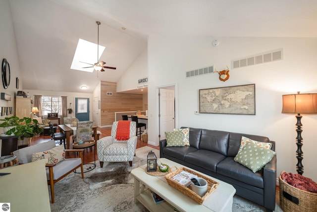 living room with ceiling fan, hardwood / wood-style flooring, high vaulted ceiling, and a skylight