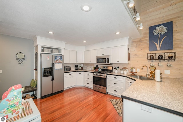 kitchen with sink, white cabinets, light hardwood / wood-style flooring, and stainless steel appliances