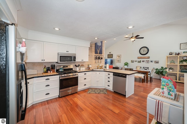 kitchen featuring stainless steel appliances, white cabinetry, kitchen peninsula, and decorative backsplash