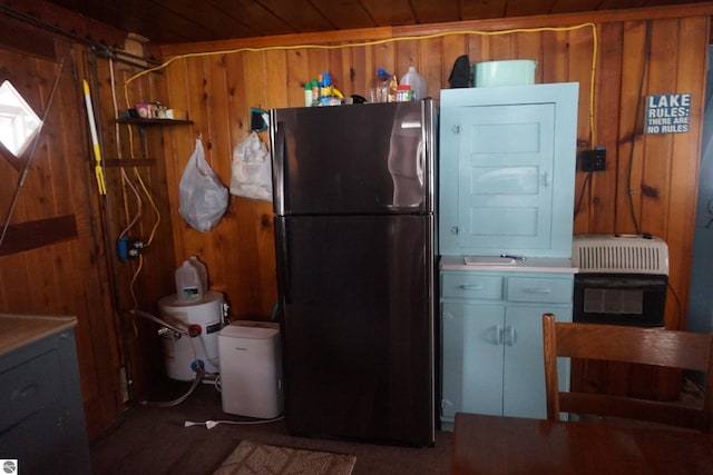 kitchen with black fridge, wood ceiling, wooden walls, and heating unit