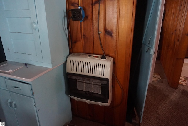 room details featuring wooden walls, carpet flooring, and heating unit